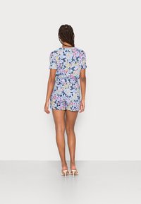 Bloemrijke romper in lichtblauw met korte mouwen, een cinched taille en een patroon van verschillende kleurrijke bloemen en bladeren. Soepele textuur.
