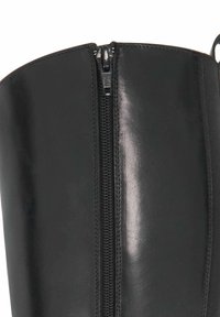 Black faux leather knee-high boot featuring a central zipper, smooth texture, and a rounded toe. The design offers a sleek, fitted silhouette.