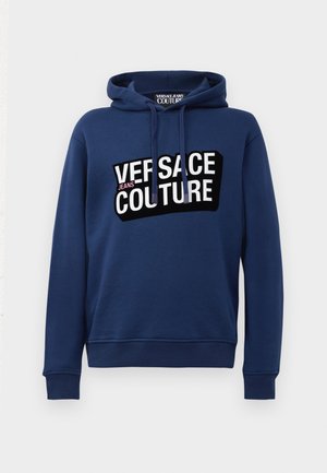 Granatowa bluza z kapturem z dużym czarno-białym nadrukiem "VERSACE JEANS COUTURE" z przodu. Wykonana z miękkiego materiału.