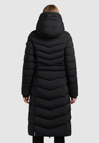 Lunga giacca a vento nera con design a zig-zag, dotata di cappuccio e vita cinchata per una silhouette aderente. Texture liscia e materiale resistente.