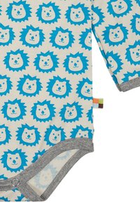 Body per neonati in cotone con sfondo crema e stampa ripetuta di teste di leone blu, rifiniture grigie e chiusure a scatto sul fondo.