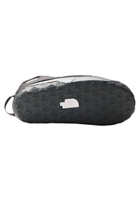 Zapatilla negra con suela de goma texturizada que presenta un patrón geométrico y un logotipo estampado. La parte superior tiene un acabado liso y costuras reforzadas.
