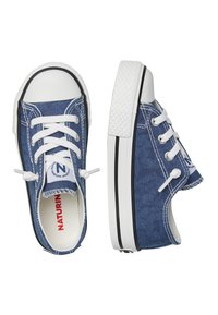 Baskets basses en denim avec lacets blancs, bout en caoutchouc et semelle blanche texturée. Le tissu bleu présente des coutures contrastées et un logo sur la languette.