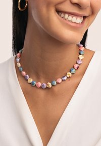 Collier coloré en perles présentant des perles en forme de coquillage rose, bleu et violet, entrecoupées d'accents dorés. Texture lisse, design circulaire.