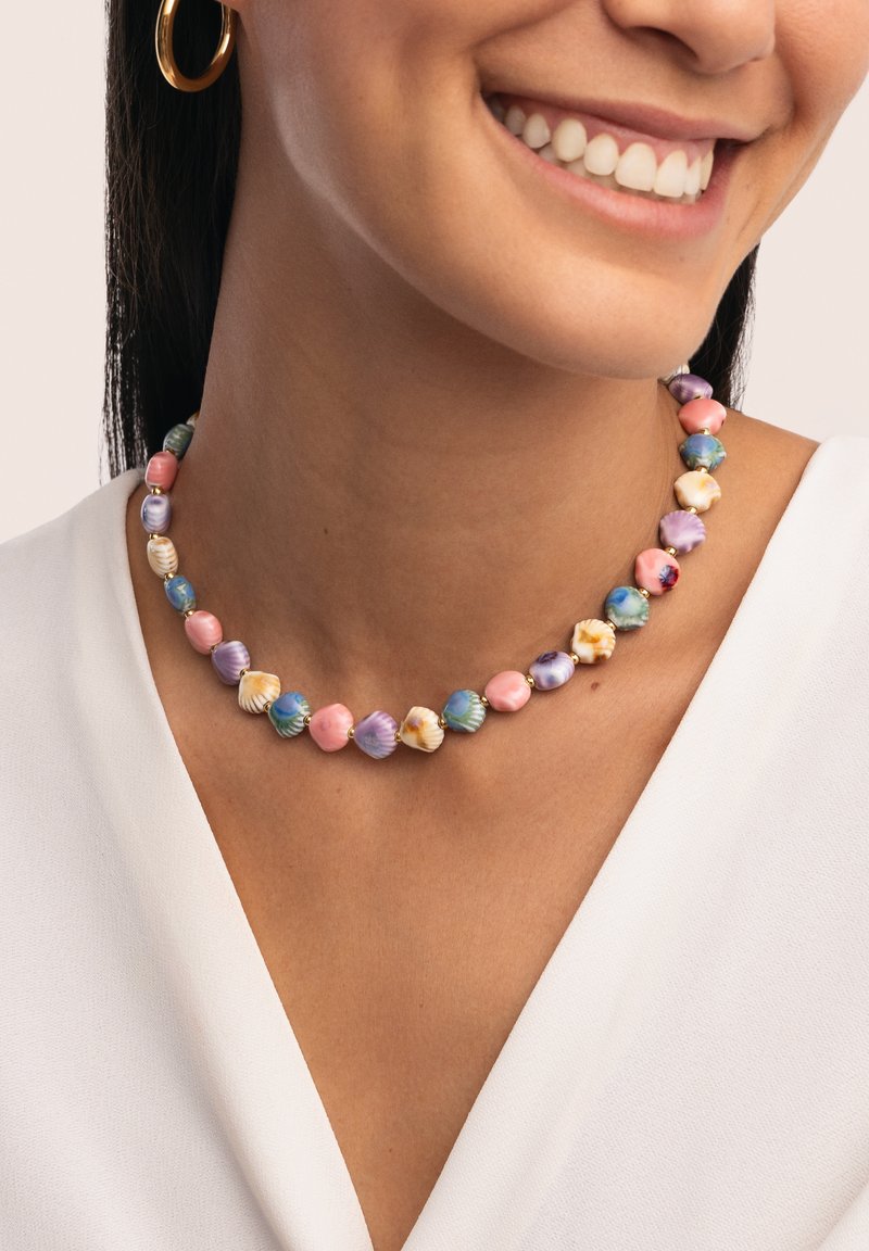 Collier coloré en perles présentant des perles en forme de coquillage rose, bleu et violet, entrecoupées d'accents dorés. Texture lisse, design circulaire.