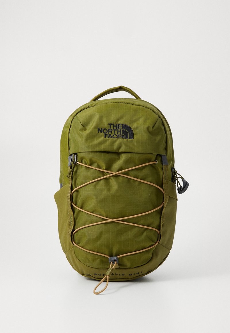 Olive žalia spalvos "North Face Borealis Mini" kuprinė su priekyje esančia elastinga virve, viršutine rankena ir šoninėmis kišenėmis, pateikta prieš baltą foną.