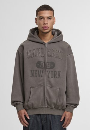 Siva jopa z zadrgo z velikim logotipom 'KARL KANI NEW YORK' v temnem tisku, s prostornim sprednjim žepom in kapuco z vrvico.