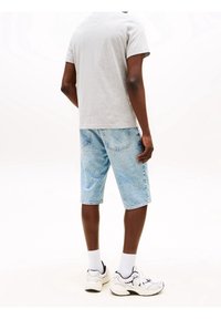 Gray short-sleeve t-shirt paired with light blue denim shorts, featuring a relaxed fit and two back pockets, worn with white sneakers and socks.