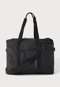 Crni pravokutni torba za putovanja s dva ručka, podesivim remenom za rame, prednjim zip džepom i malim bijelim natpisom branda na rubu džepa.