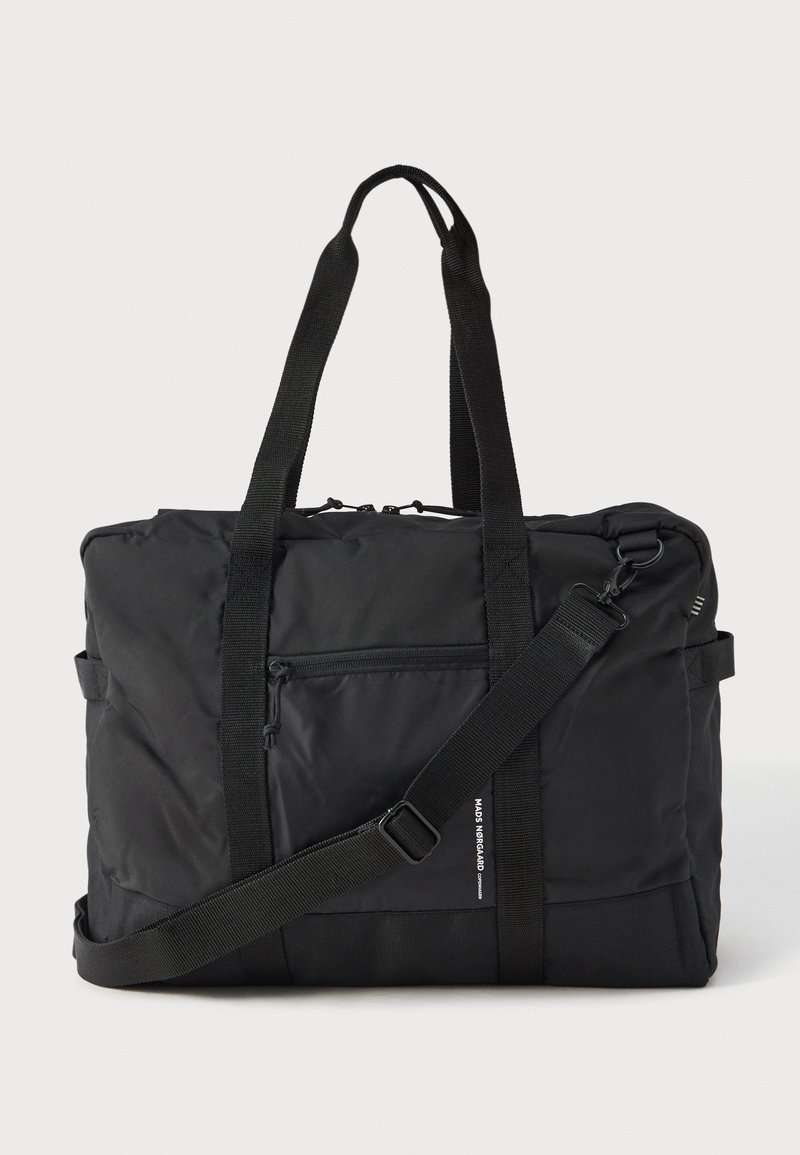 Crni pravokutni torba za putovanja s dva ručka, podesivim remenom za rame, prednjim zip džepom i malim bijelim natpisom branda na rubu džepa.