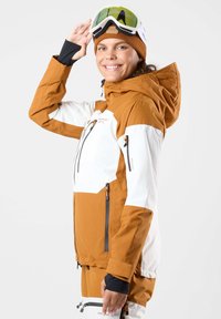 Giacca da sci in tessuto arancione e bianco con tasche con zip, cappuccio regolabile e vestibilità aderente. Include dettagli neri nei polsini.