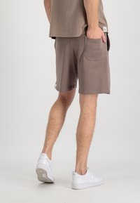 Pánske svetlohnedé šortky vyrobené z jemnej tkaniny s voľným strihom. Obsahujú bočné vrecko a majú neformálnu dĺžku, doplnené bielymi teniskami.