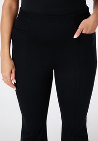Zwarte, slimfit broek van gestructureerde stof, met twee zijzakken en een gladde tailleband, ontworpen voor een stijlvolle uitstraling.
