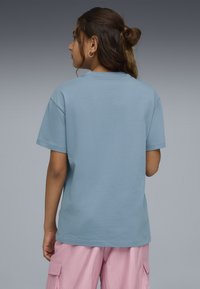 Lyseblå kortærmet T-shirt lavet af blødt bomuld. Enkel design med rund hals og afslappet pasform, kombineret med pink cargo-bukser.