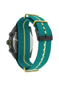 Tyrkysový textilný remienok na hodinky so žltým prešívaním a zlatou sponou, spárovaný s čiernym textúrovaným puzdrom na hodinky a viacfarebnými gombíkmi.