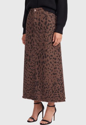 Falda midi marrón con estampado irregular de leopardo negro, bajo sin rematar, combinada con suéter de punto negro y sandalias negras de tacón alto con correa en el tobillo.