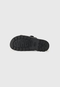 Black rubber outsole with deep tread and embossed "COACH" logo. Features a textured surface and sturdy construction for durability.