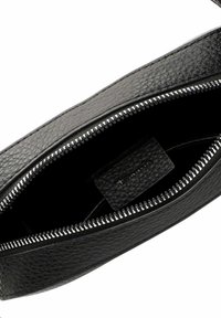Black leather pouch with a textured surface, zip closure, and a smooth interior. Features a brand tag inside.