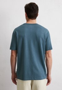 Blauwe katoenen t-shirt met korte mouwen, ronde hals en een relaxte pasvorm. De stof voelt zacht aan en heeft een gladde textuur.