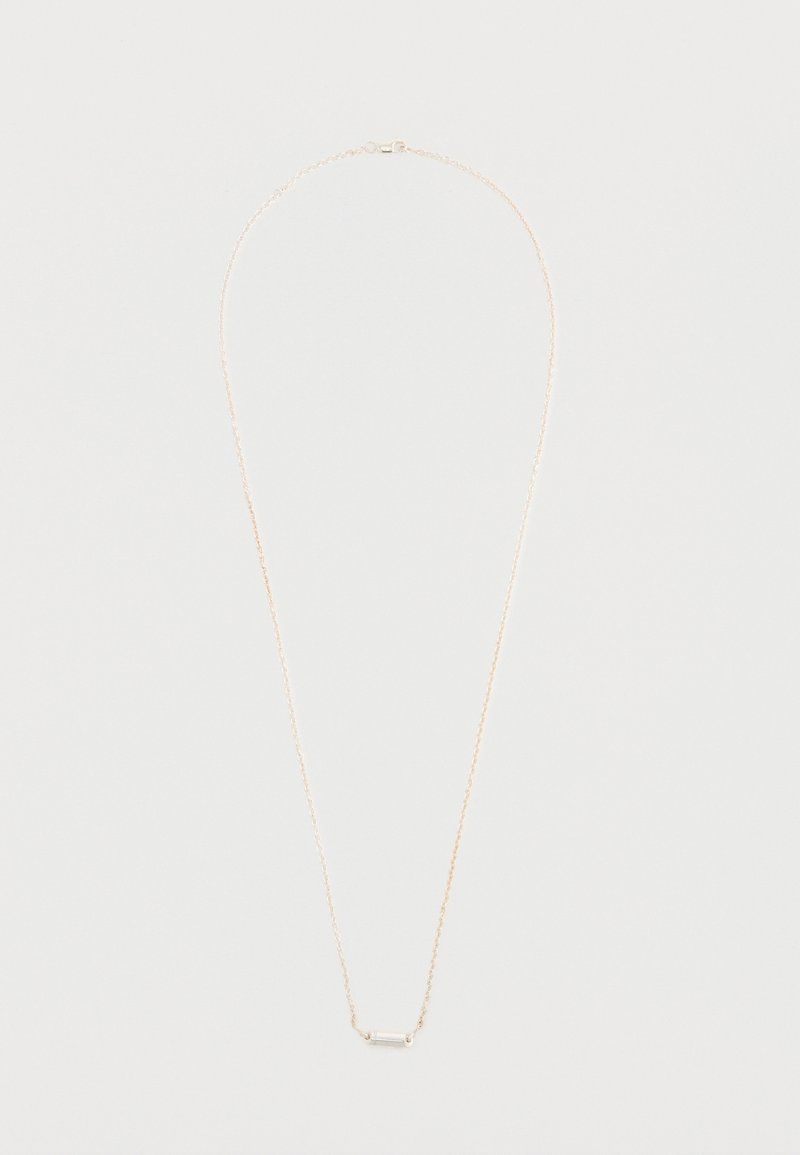 Kuldse tooniga kaelakee õrna ahelaga ja horisontaalse baarikujulise ripatsiga, millel on kristallaktsent. Sile pind, minimalistlik disain.