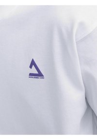 Tessuto della felpa bianca con una trama liscia, con un logo triangolare viola e il testo "JACK & JONES CORE" sul lato sinistro.