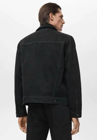 Črna jeans jakna s sproščenim prileganjem, s koničastim ovratnikom in zapenjanjem na zapenjanje. Ima šiv na hrbtni strani yoke in dve hrbtni žep.