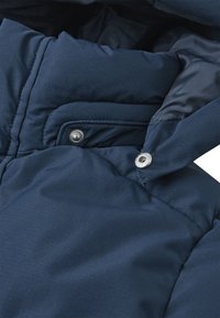 Giacca trapuntata blu navy con texture a quadri, dotata di un alto colletto e dettagli con bottoni a pressione argentati sul davanti. Interno morbido.