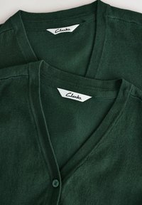 Grön cardigan-set med V-ringning, tillverkat av mjukt material. Har knappstängning och "Clarks"-etikett vid halsen.