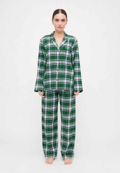 Ensemble de pyjama à motif tartan vert composé d'une chemise à boutons et d'un pantalon ample, fabriqué dans un tissu doux, avec des accents blancs.