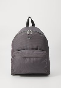 Grå nylon ryggsekk med rund form, som har en frontlomme med glidelås, doble topplommer med glidelås og en svart logo-lapp. Strukturert overflate.