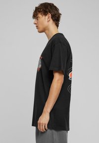 Sort bomuld t-shirt med korte ærmer, med et grafisk design på forsiden og rund halsudskæring. Blød tekstur og afslappet pasform.