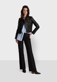 Black leather motorcycle jacket over a light blue button-up shirt. Paired with black flared pants and pointed black heeled boots.