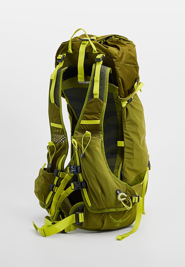 Mochila verde oliva con panel trasero de malla, correas ajustables, múltiples hebillas y acentos en amarillo neón. Tela duradera con cierre enrollable.