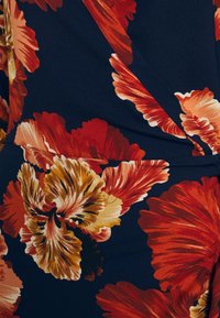 Tissu à motifs floraux présentant de grandes fleurs rouges et beiges sur un fond bleu foncé, texturé avec une finition douce et lisse.