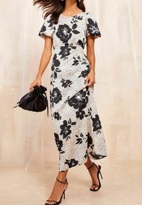 Černobílé květinové šaty s puntíkovaným vzorem; krátké puff rukávy, dlouhý volný střih, spárované s černou taškou na stažení a podpatky.