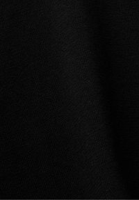 Tissu noir tricoté avec un motif de tissage serré et des plis subtils créant des ombres douces.
