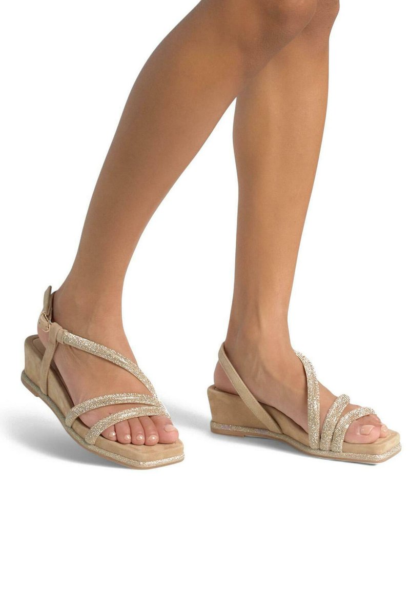 Sandales compensées beige avec plusieurs sangles ornées de paillettes. Matière en suède doux avec un semelle intérieure confortable et un design ouvert.
