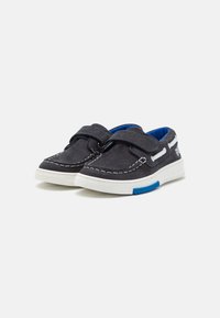 Scarpe in suede blu navy con dettagli cuciti bianchi, dotate di una fodera interna blu e una suola bianca con dettagli blu. Chiusura con strap in Velcro.