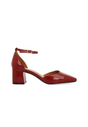 Zapato de charol rojo con punta afilada y tacón medio tipo bloque, que cuenta con una correa en el tobillo con un detalle de hebilla plateada. Textura suave.