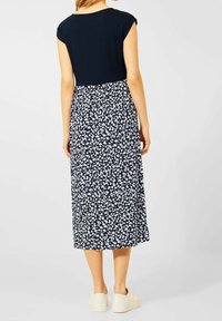 Granatowa sukienka z dopasowaną górą i spódnicą w kwiatowy wzór w kolorze białym. Długość do połowy łydki, z krótkimi rękawami i zwiewnym fasonem.