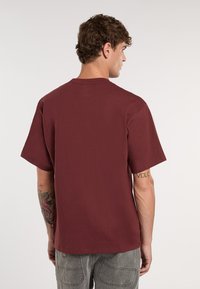 Marošová tričko s krátkým rukávem a kulatým výstřihem, vyrobené z měkké tkaniny. Má jednoduchý design, viditelné švy a malé logo na lemu.