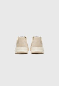 Beige Wildleder-Sneaker mit geschwungenem Design, gepolsterter Schuhkragen und dicker, off-white Sohle. Verfügt über eine glatte Textur und minimale Markenkennzeichnung.