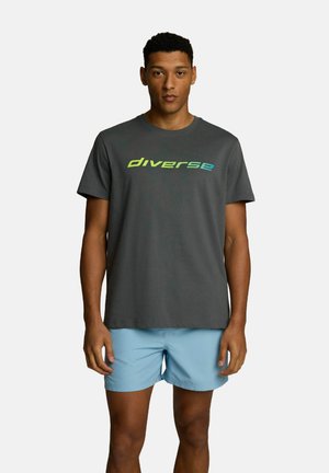 Szara bawełniana koszulka z napisem "diverse" w gradientowych odcieniach niebieskiego i zielonego. Połączona z jasnoniebieskimi szortami, tworząc swobodny look.
