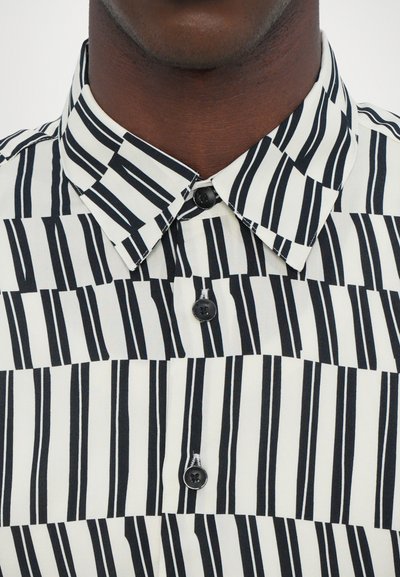 Black and white striped shirt featuring a classic collar, button closure, and a mix of thick and thin vertical stripes on a smooth fabric.