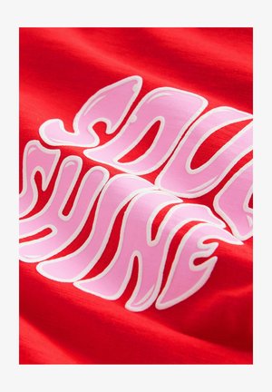 Tessuto rosso con grandi lettere ondulate rosa e bianche che formano una parola o frase parzialmente visibile.