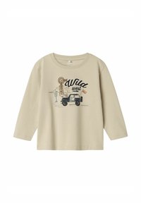 Beige pitkähihaisessa paidassa on edessä tuulivoimala, vuoria ja ajoneuvo, jossa on mustalla kirjoitettu "Wild West" -teksti. Materiaali on puuvillaa ja malli on rento.