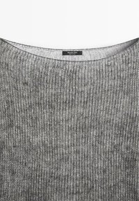 Grå strikket sweater med en bred halsudskæring, der har et struktureret mønster og en label med teksten "Massimo Dutti" indeni.