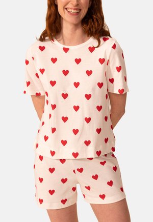 Ensemble de pyjama en coton blanc comprenant un T-shirt et un short, tous deux ornés d'un motif de cœurs rouges, à manches courtes et à coupe ample.