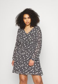 Vestido floral com fundo azul marinho, apresentando um decote em V, mangas longas e uma cintura ajustada. O padrão inclui pequenas flores brancas.