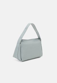 Svetlo siva, teksturirana torba za rame z enim trakom, ki nosi logotip Calvin Klein. Pravokotna oblika s gladkim, strukturiranim dizajnom.